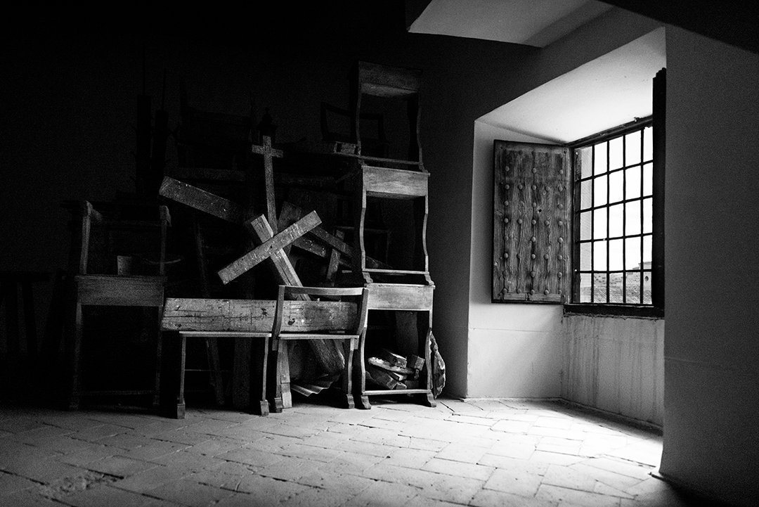 Stacked chairs in a room beside a window.